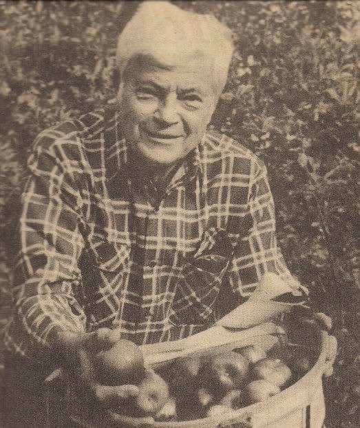 A sepia toned photo of Joseph Simon holding a backset of freshly picked apples.